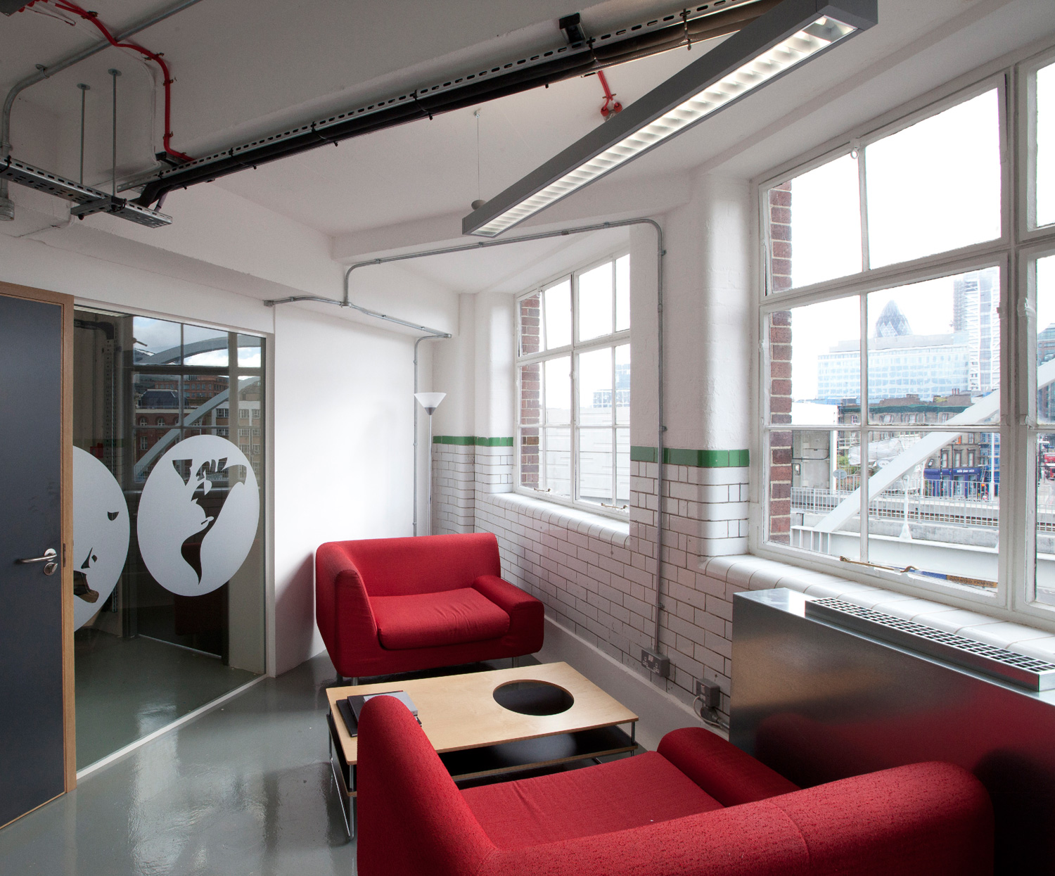 Industrial open plan office design - informal meeting room retains original tiles