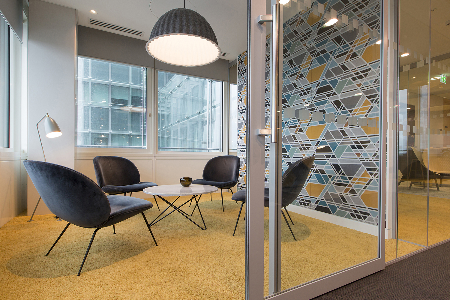 London headquarters interior architecture redesign - informal meeting room with lounge chairs, coffee table and feature lighting and wall fabric