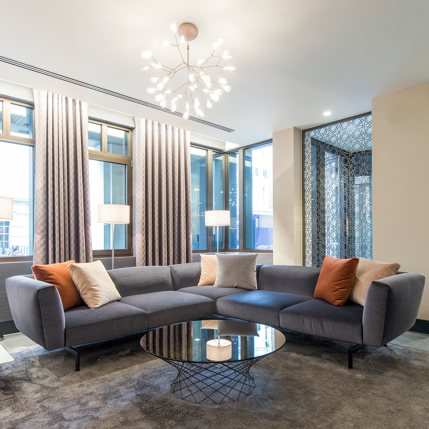 Plush Mayfair reception and waiting area design - beautiful velvet corner sofa with feature coffee table and pendant lighting